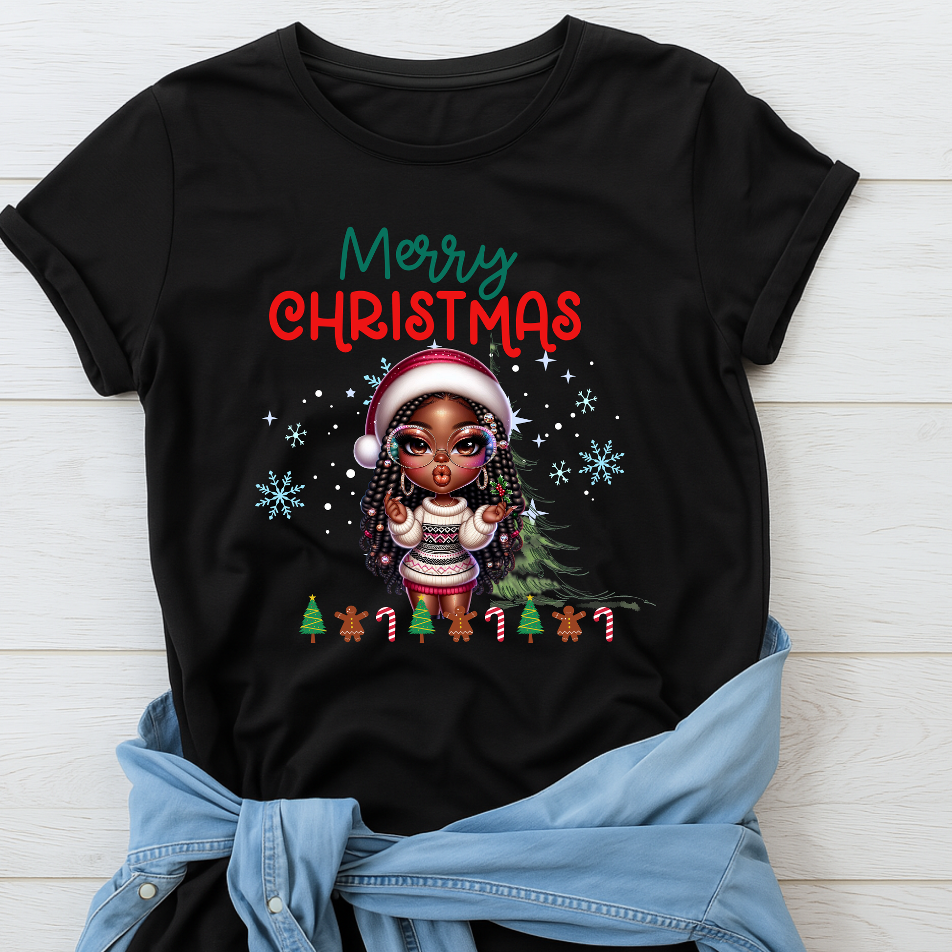 Black t-shirt with Christmas design featuring a child in a Santa hat and tree, on a light wooden background.